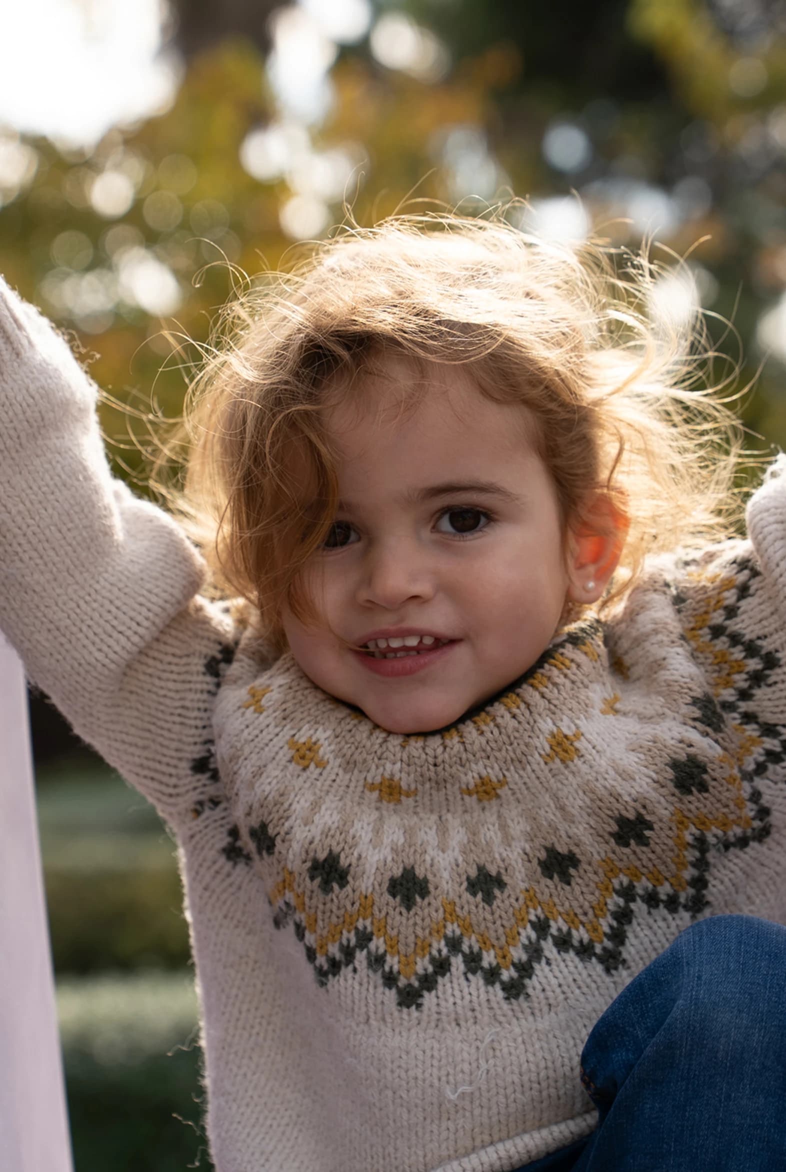 Imagen de una niña encima de un tobogán sonriendo a la cámara.
