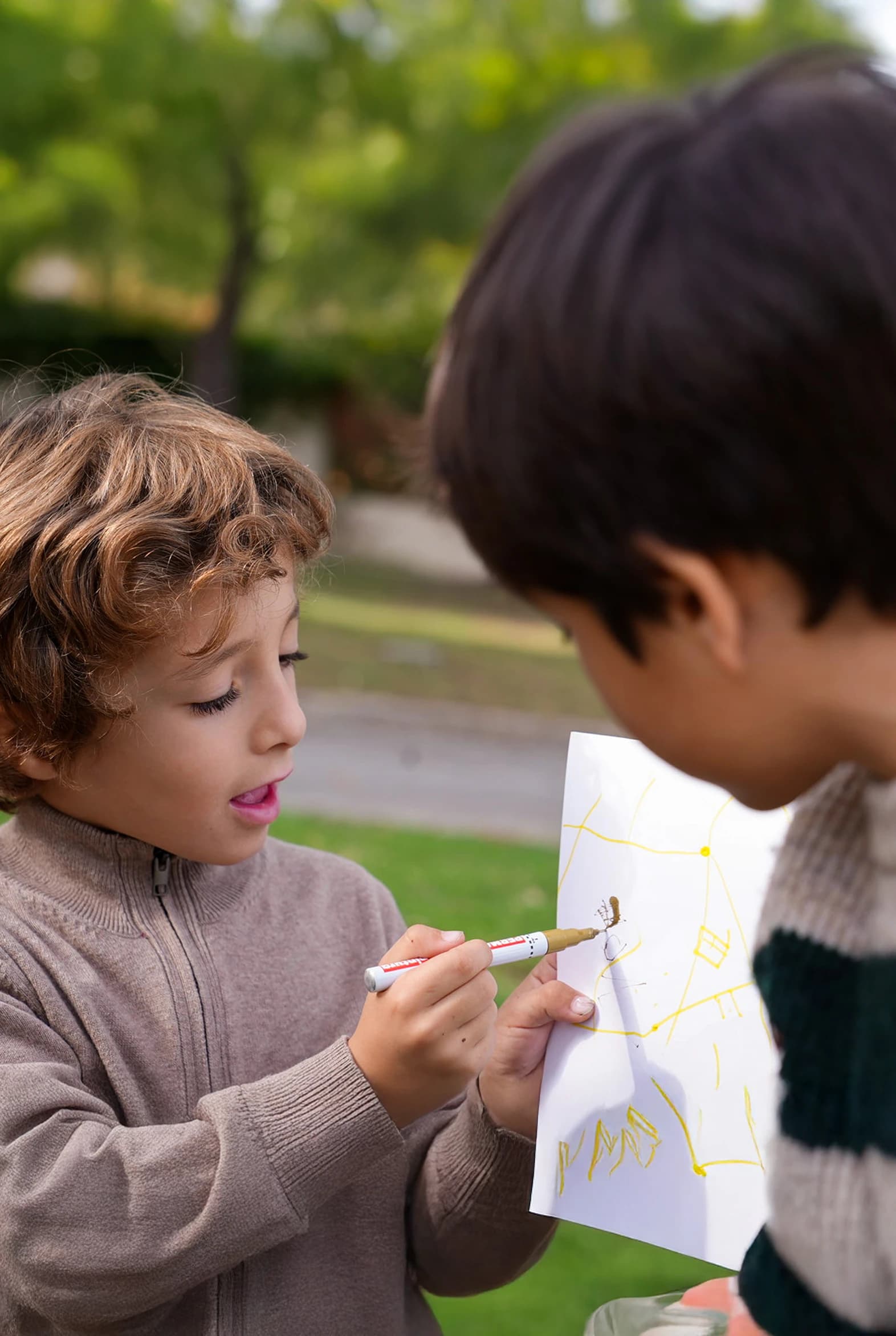 Imagen de un niño enseñandole su dibujo a su amigo.