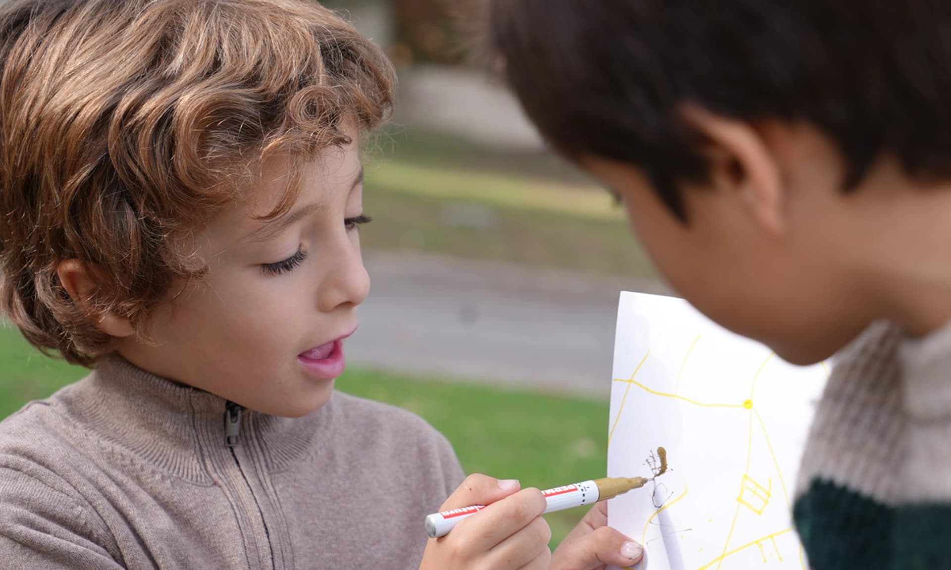 Imagen de un niño enseñandole su dibujo a su amigo.