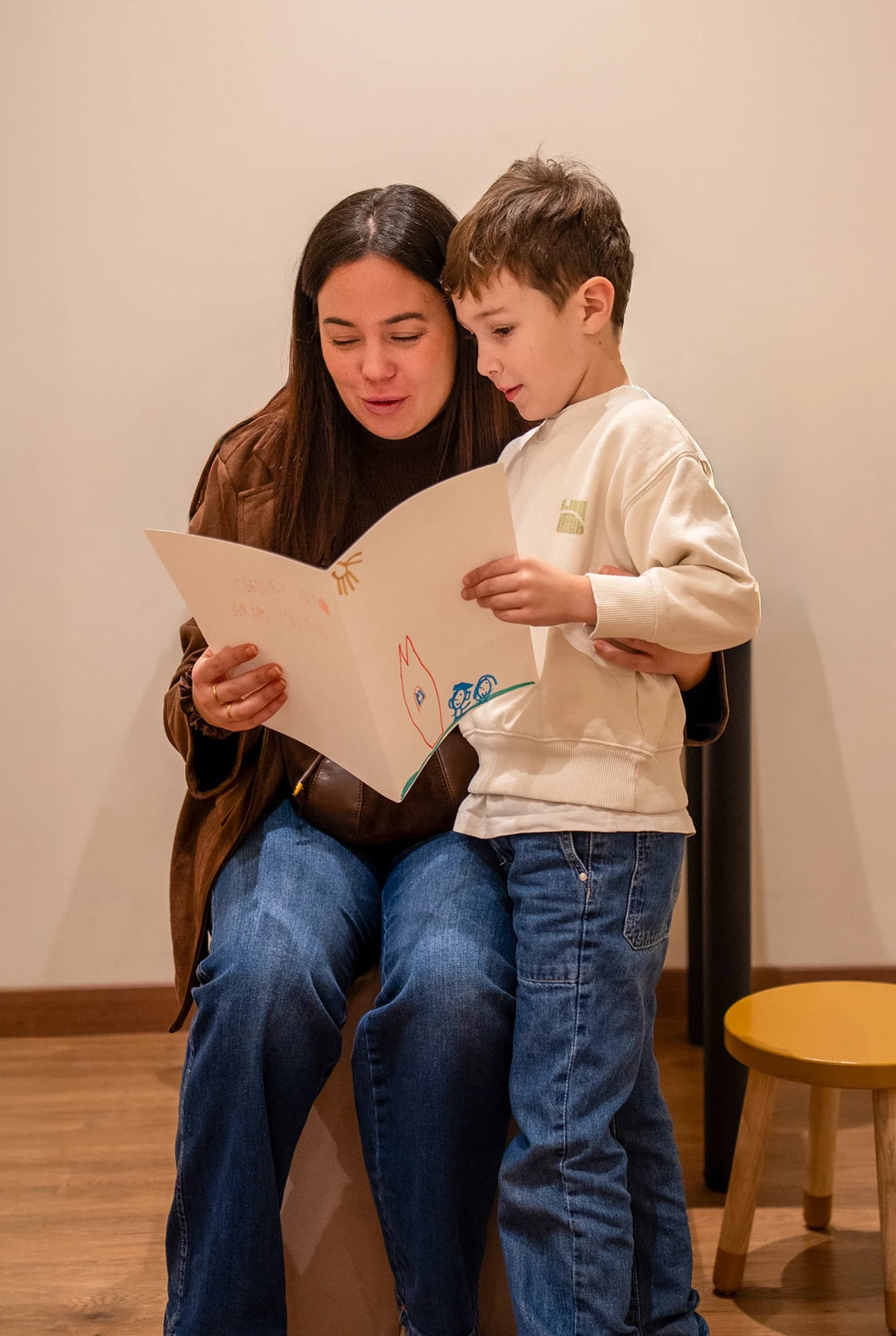 Imagen de una mujer y un niño leyendo un libro juntos.