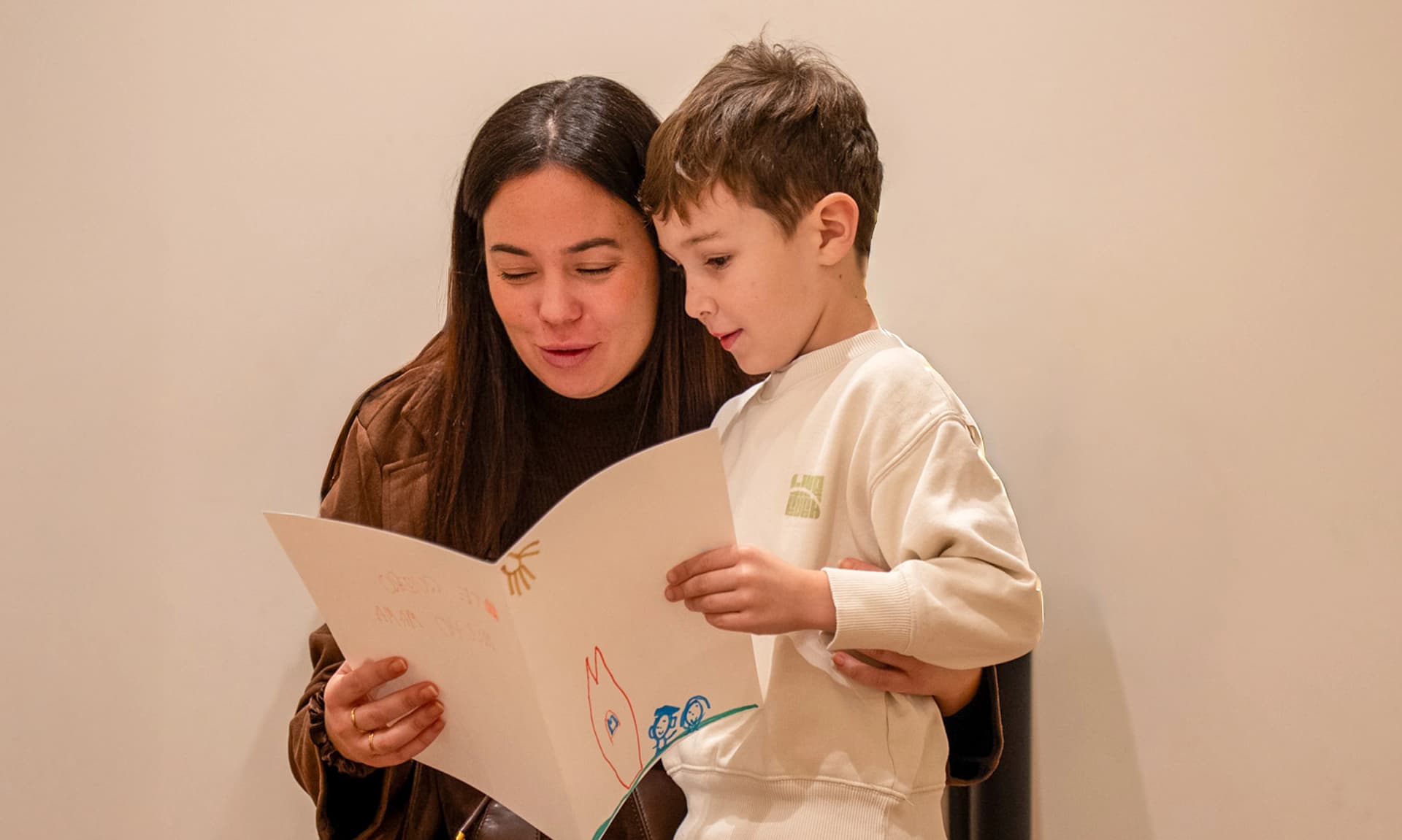 Imagen de una mujer y un niño leyendo un libro juntos.