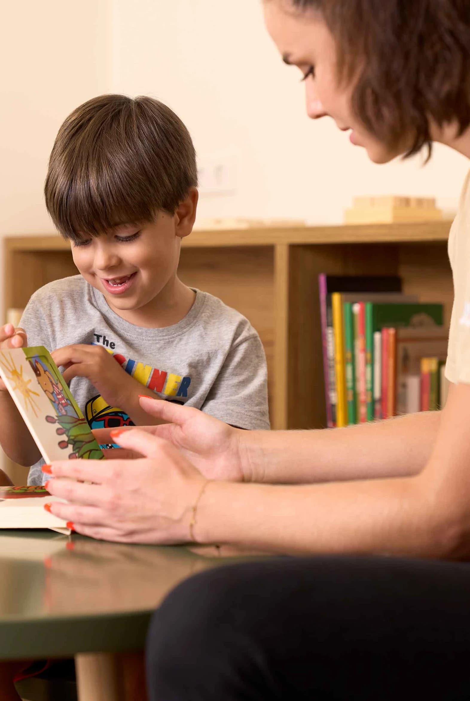 Imagen un niño aprendiendo en una mesa con su profesora.