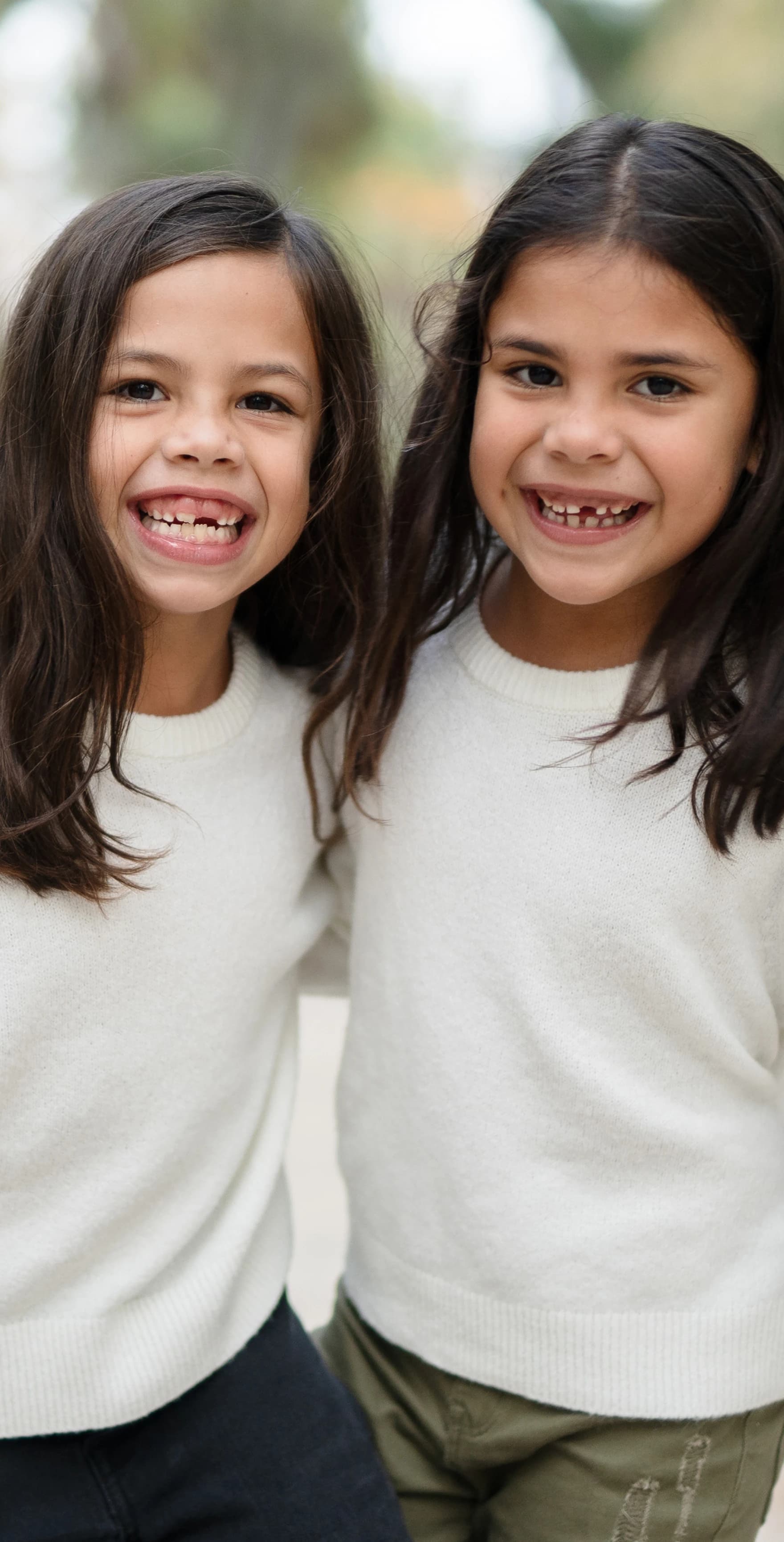 Imagen de dos niñas cogidas mirando a la cámara sonriendo.