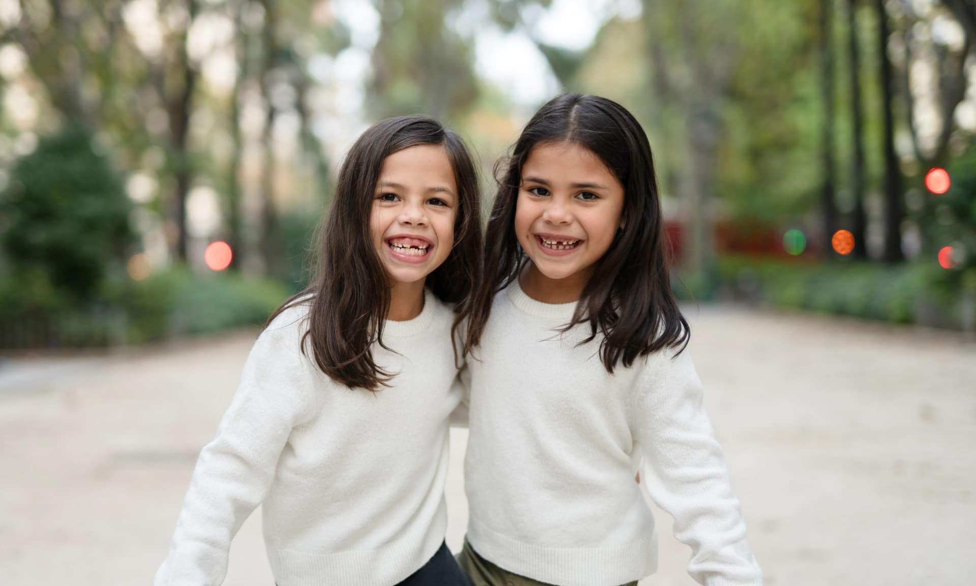 Imagen de dos niñas cogidas mirando a la cámara sonriendo.